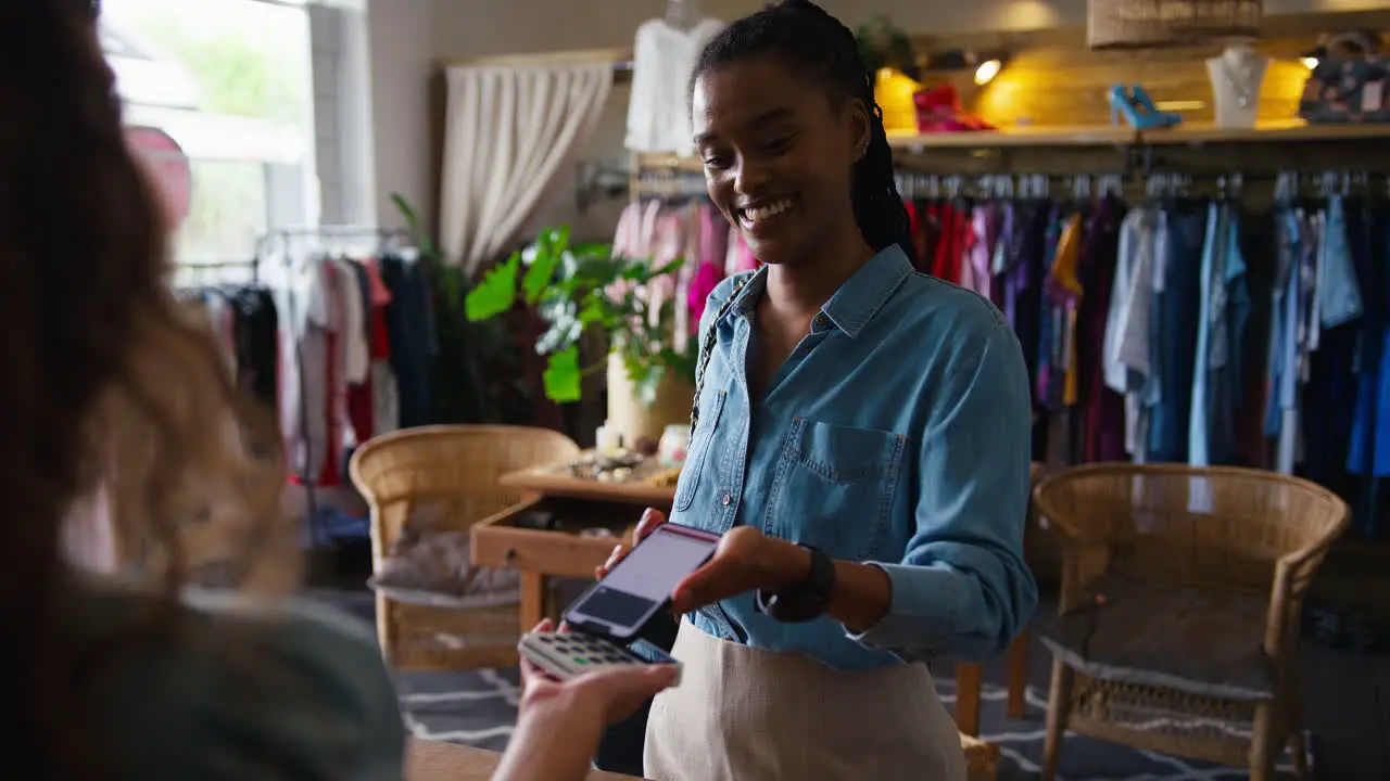 Female Customer In Fashion Store Paying For Clothes With Contactless Mobile Phone Payment App