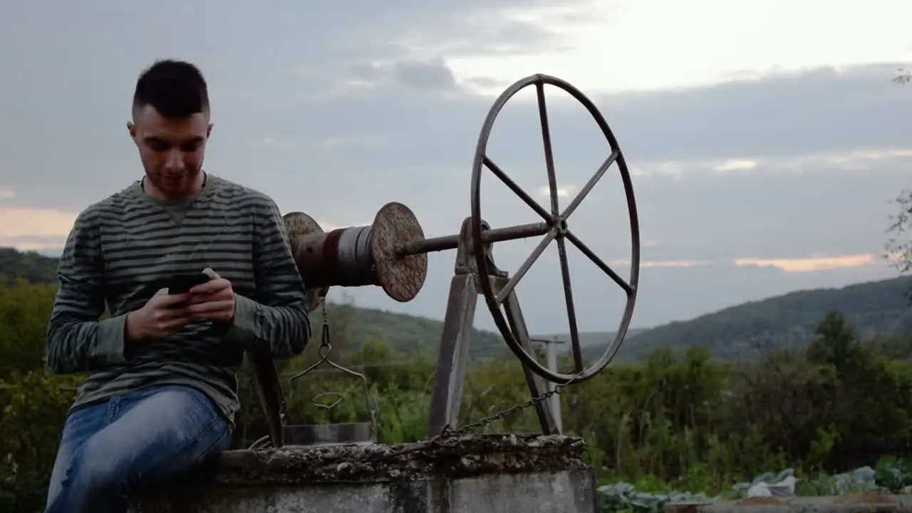 Young man texts on his cell phone in a rural setting