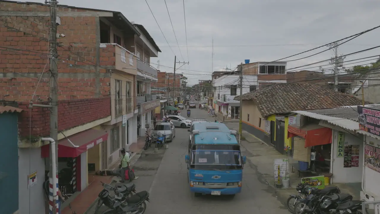 Aerial flyover of a street in Colombia with a bus slowly passing underneath