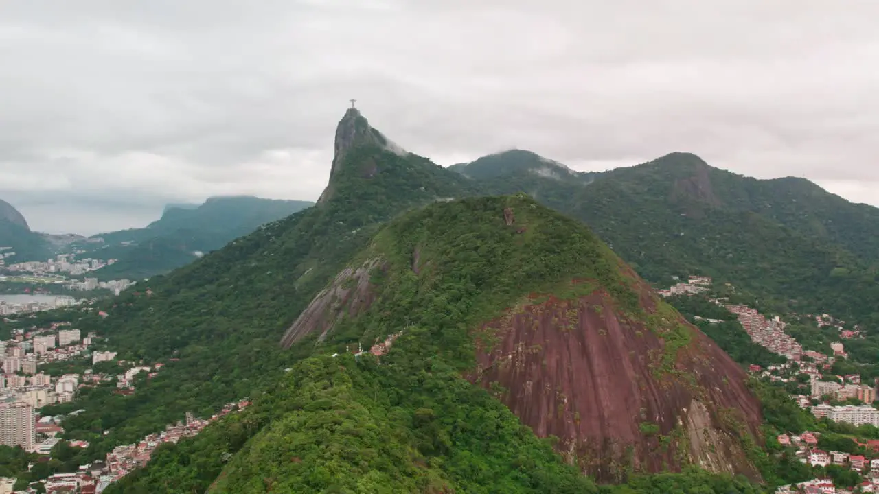 Dolly in aerial view of the dense mountains with Corcovado hill and Christ the Redeemer Rio de Janeiro Brazil cloudy day