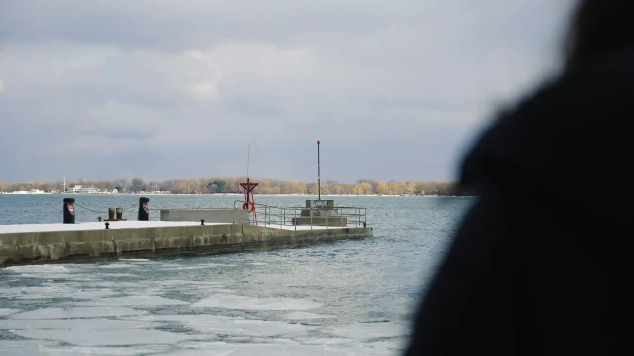 An "over the shoulder" shot of a boat dock with beach waves in slow motion during a cloudy day