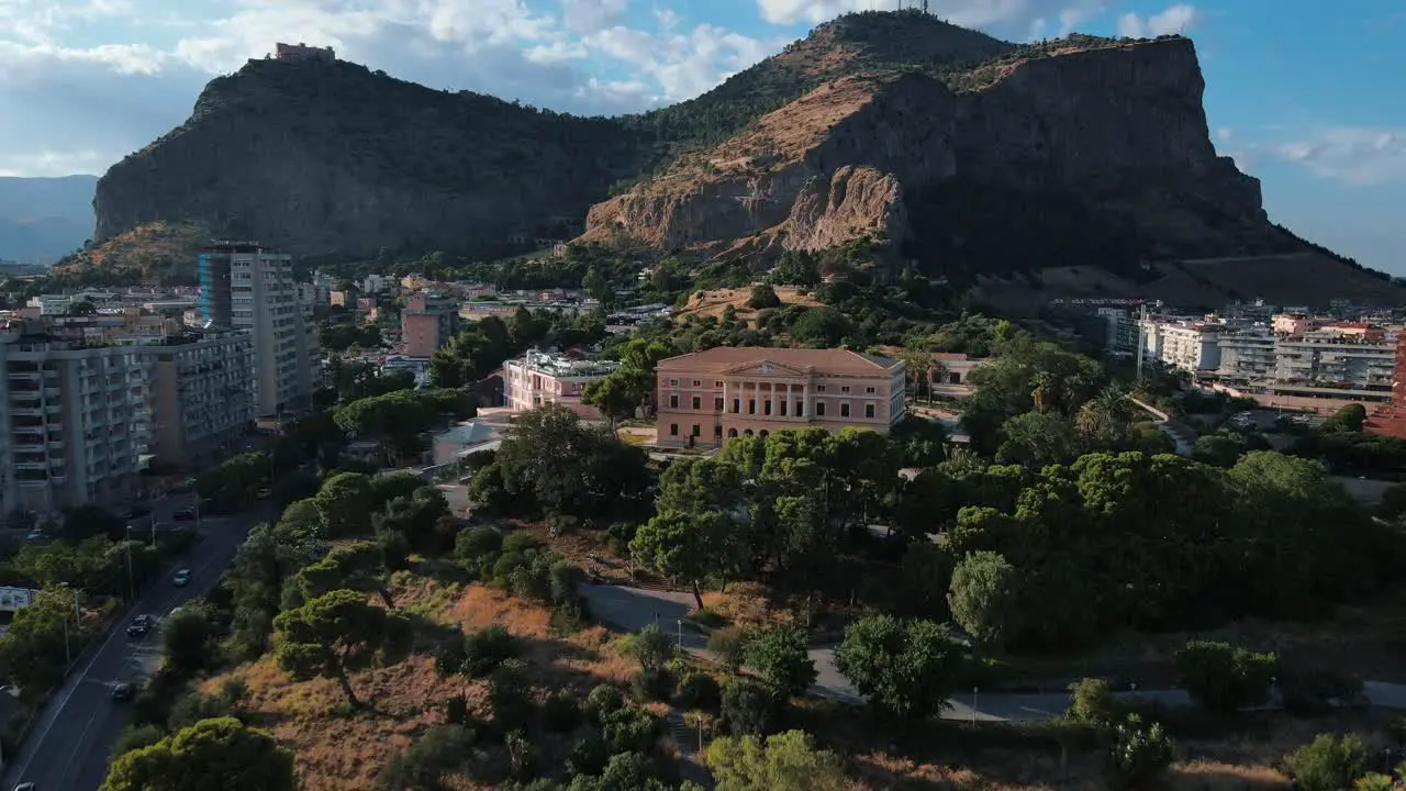 drone flying away from Mount Pellegrino mountain while Villa Belmonte is visible in the middle of the frame