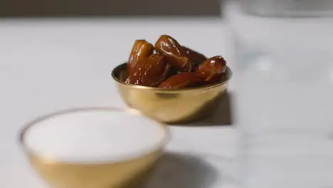 Close Up Of Bowl Of Dates With Sugar And Glass Of Water On Marble Surface Celebrating Muslim Festival Of Eid