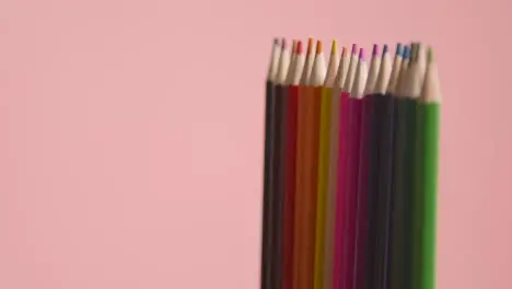 Studio Shot Of Rotating Line Of Multi-Coloured Pencils Against Pink Background 1