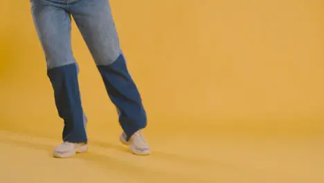 Close Up On Legs And Feet Of Woman Having Fun Dancing Against Yellow Studio Background