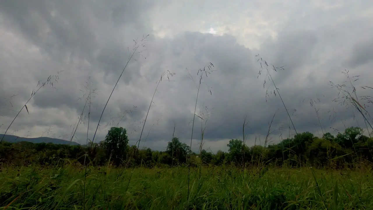 Stormy skies dark clouds time lapse in a meadow with trees forests and mountains in the background