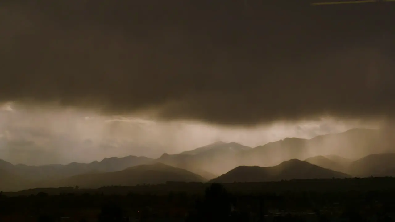 Timelapse of mountains with transition from a sunny city to a rain storm 4K