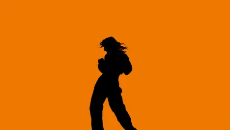 Studio Silhouette Of Woman Dancing Against Orange Background