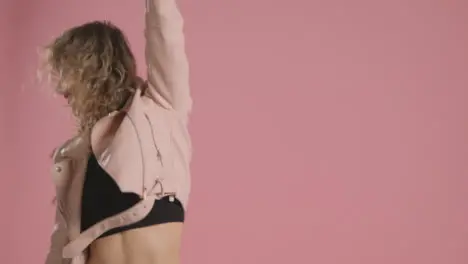 Studio Shot Of Young Woman Having Fun Dancing Against Pink Background