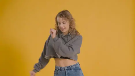 Studio Shot Of Young Woman Having Fun Dancing Against Yellow Background