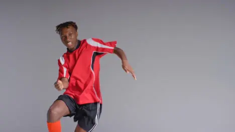 Young Male Footballer In Studio Running and Heading Ball 3