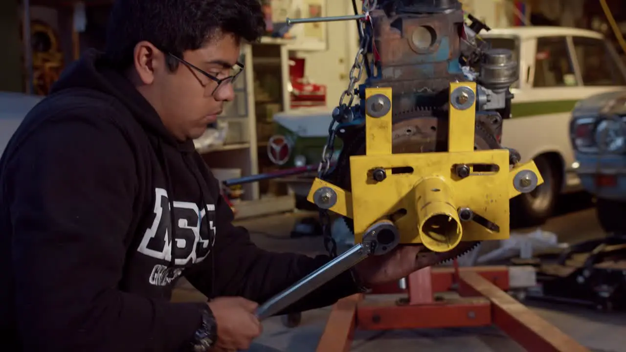 Young mechanic tightening bolts on an engine stand with a wrench