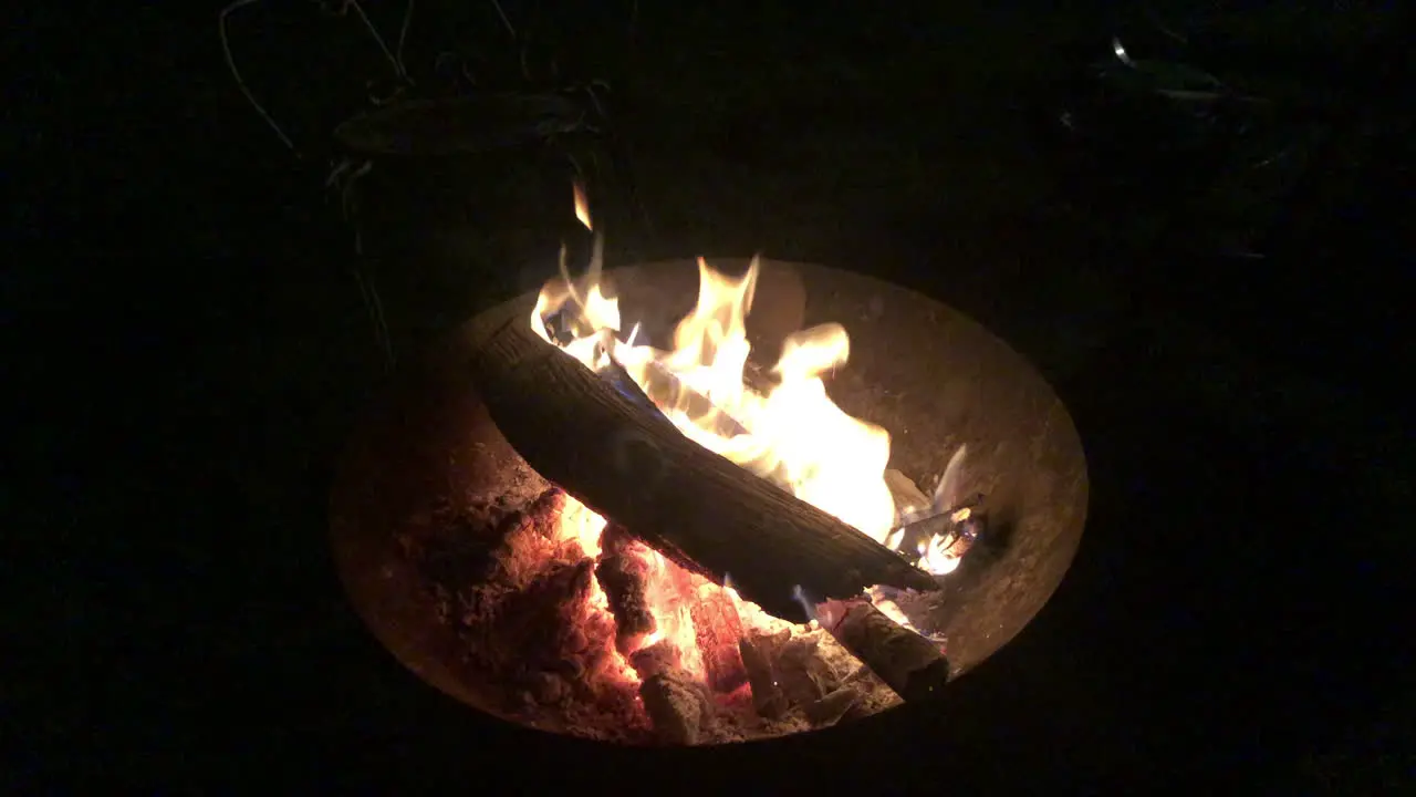 Logs burning in a fire bowl on a pitch black night