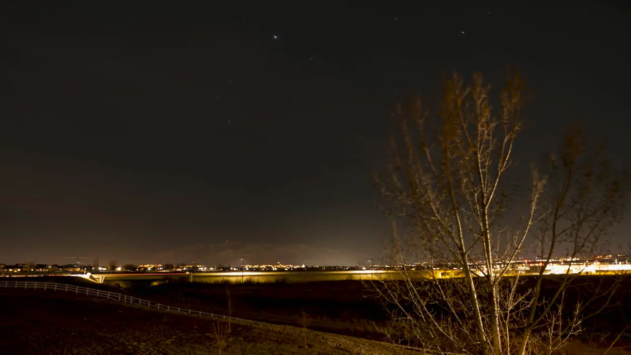 Stars and light trails from airplanes crossing the night sky in a suburban community time lapse