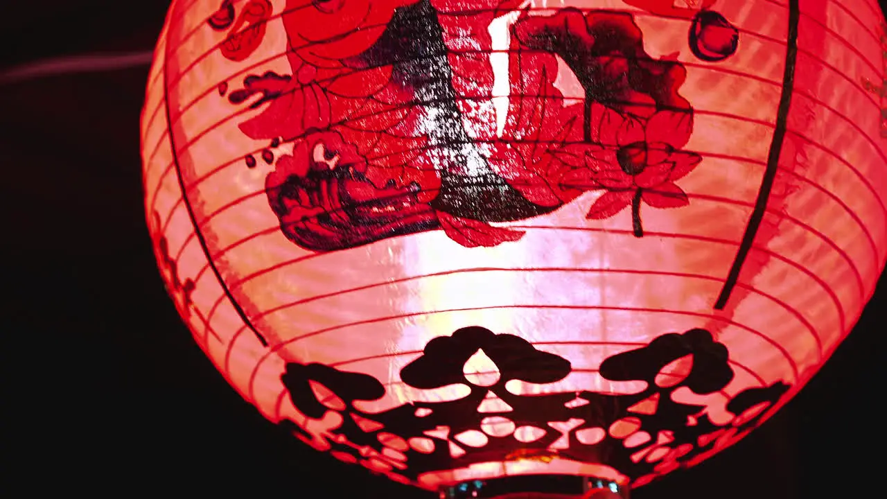 Red paper lantern with asian symbols and fringes hanging in night