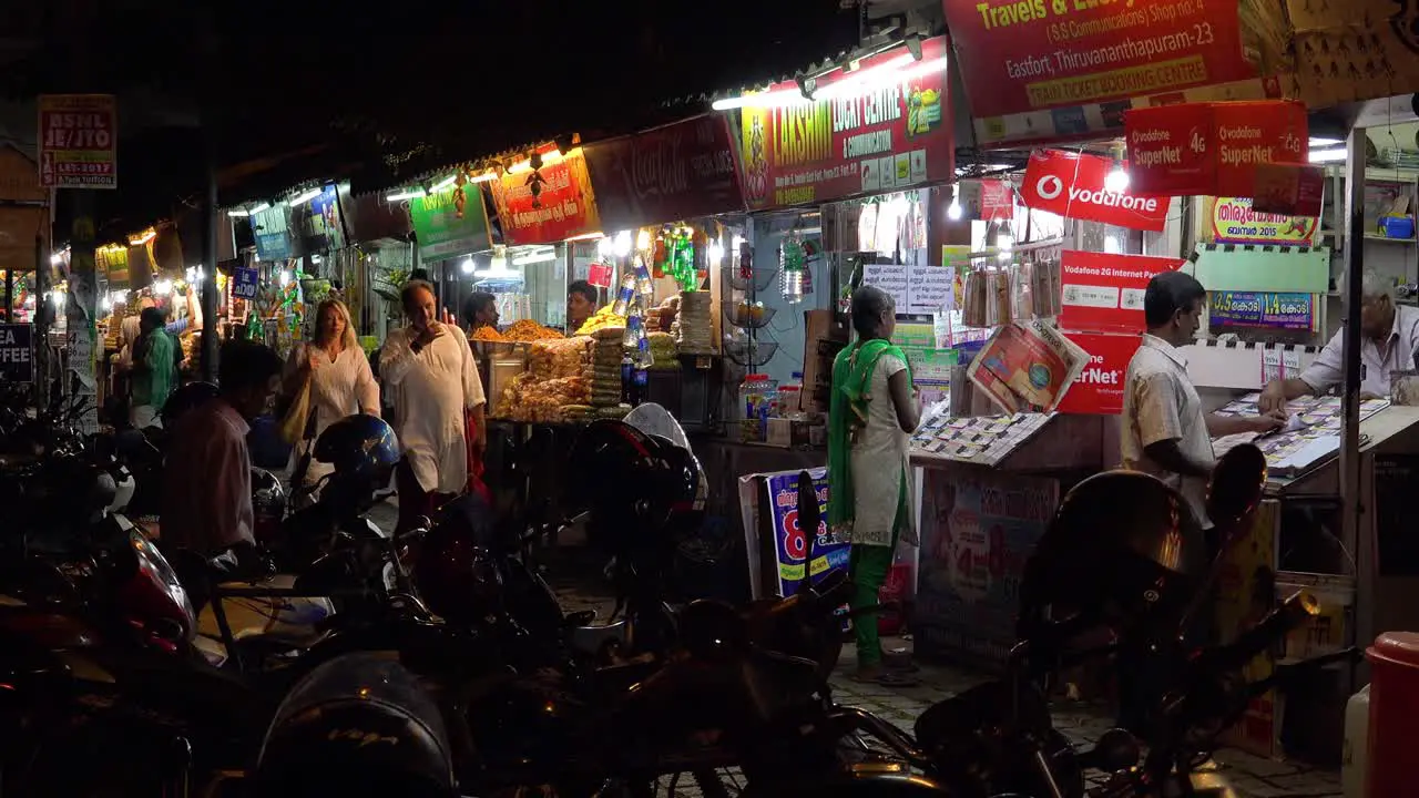 A man and woman walk through a night market in India