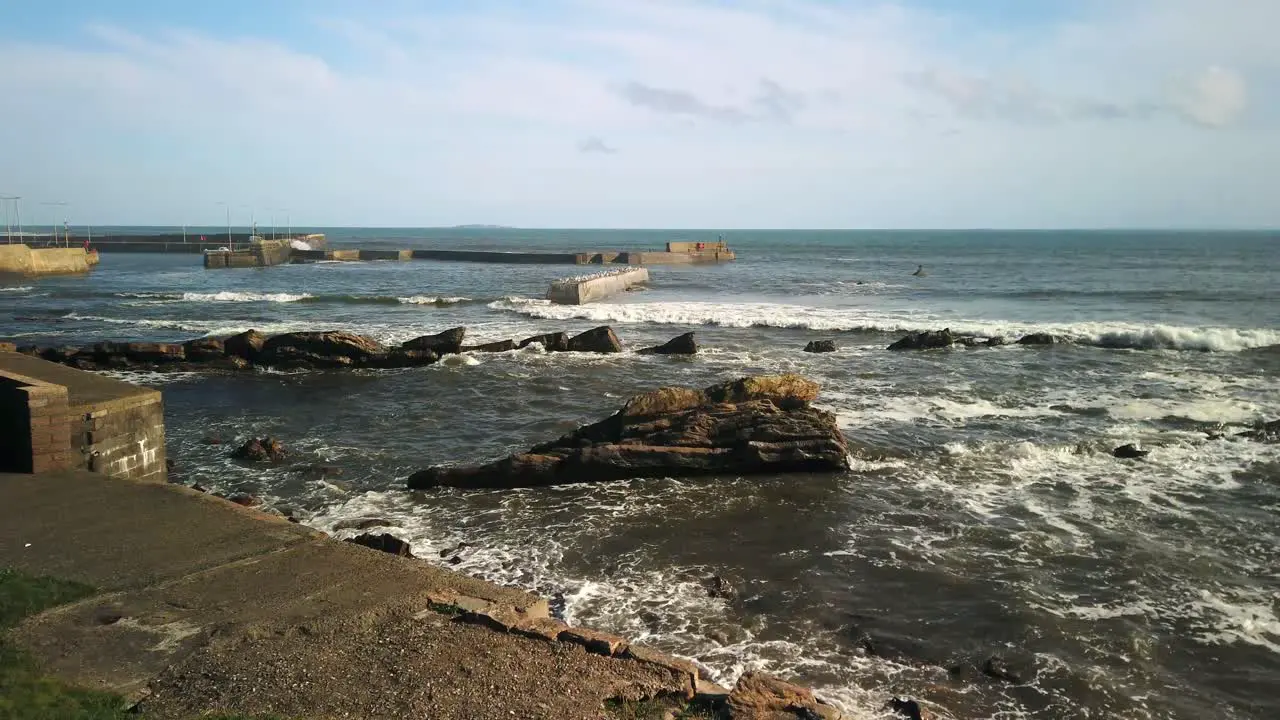 Waves rolling in and breaking on the harbour wall and shore