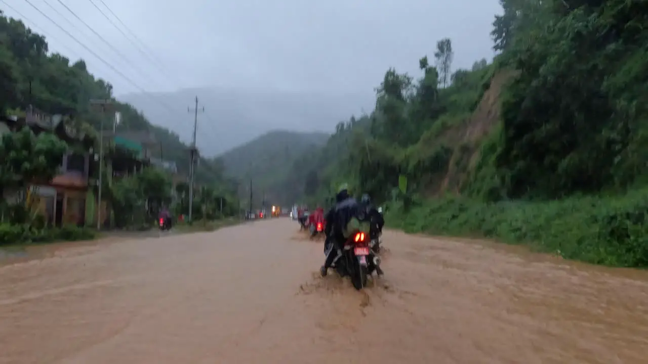 Motorcycles driving on a road flooded by very muddy storm waters during a typhoon in Nepal