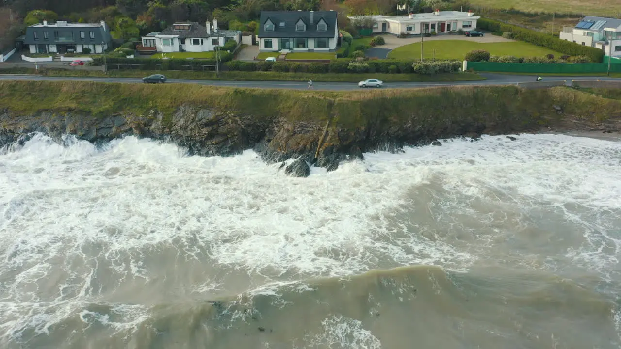 Aerial view of waves crashing against rocks along the coastline during a storm