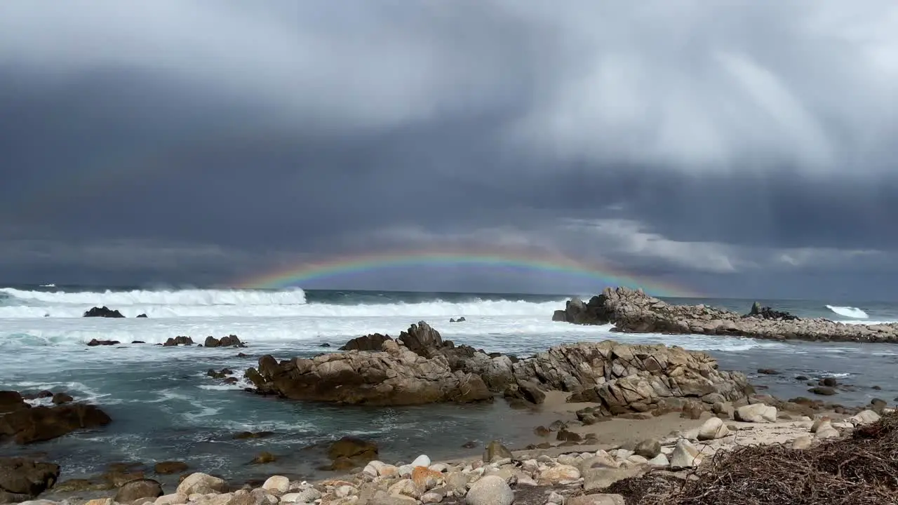 Rainbow on horizon seen from beach on stormy day