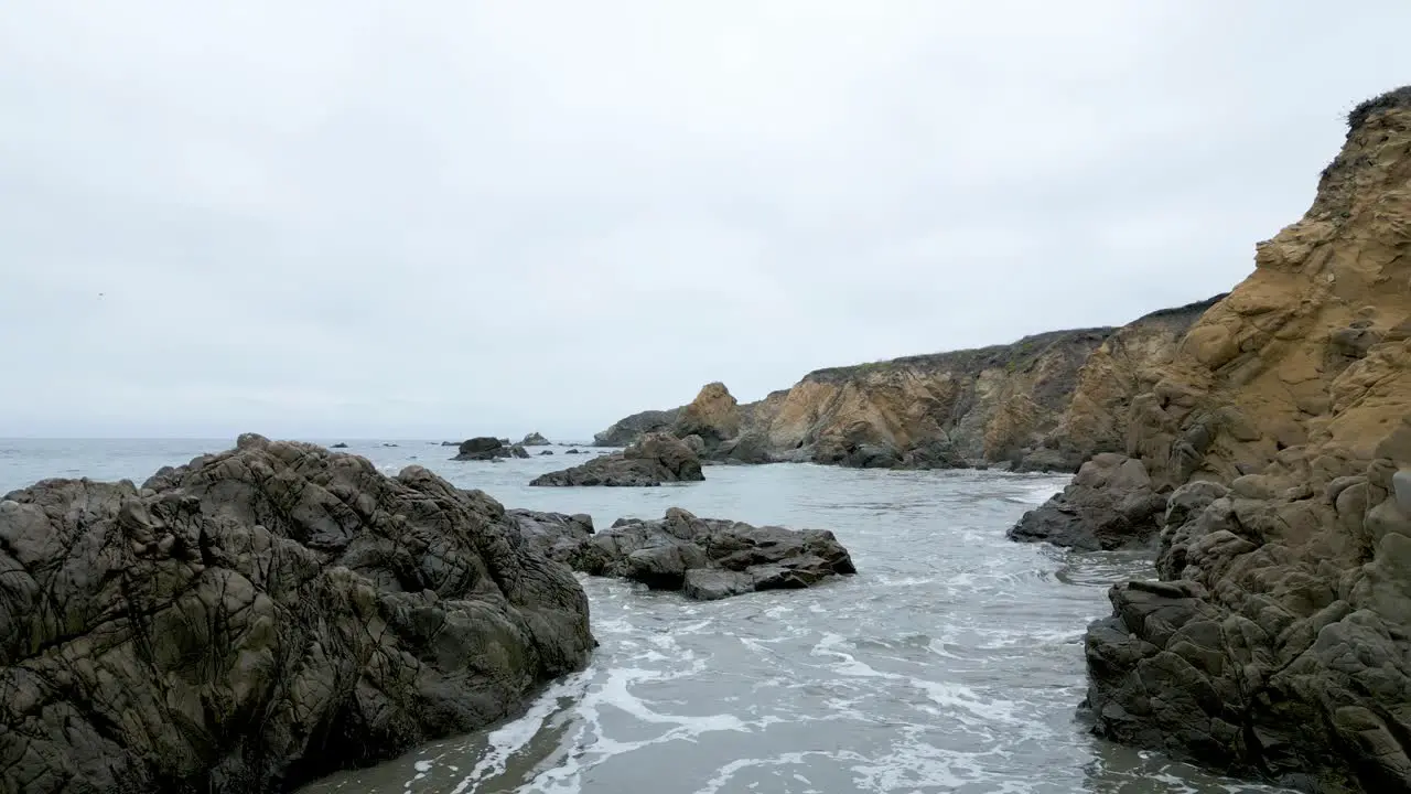 Flying low over the ocean in San Mateo County beach over rocks and waves California