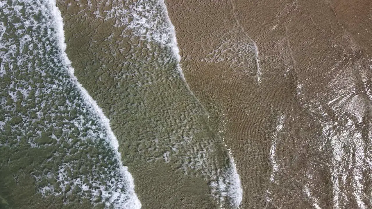 aerial view of waves breaking on a tropical beach