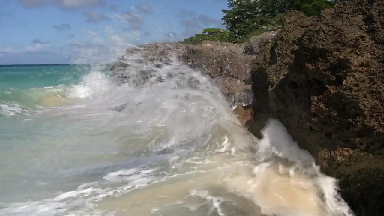 Carribean ocean waves crashing against the rocks splashing camera