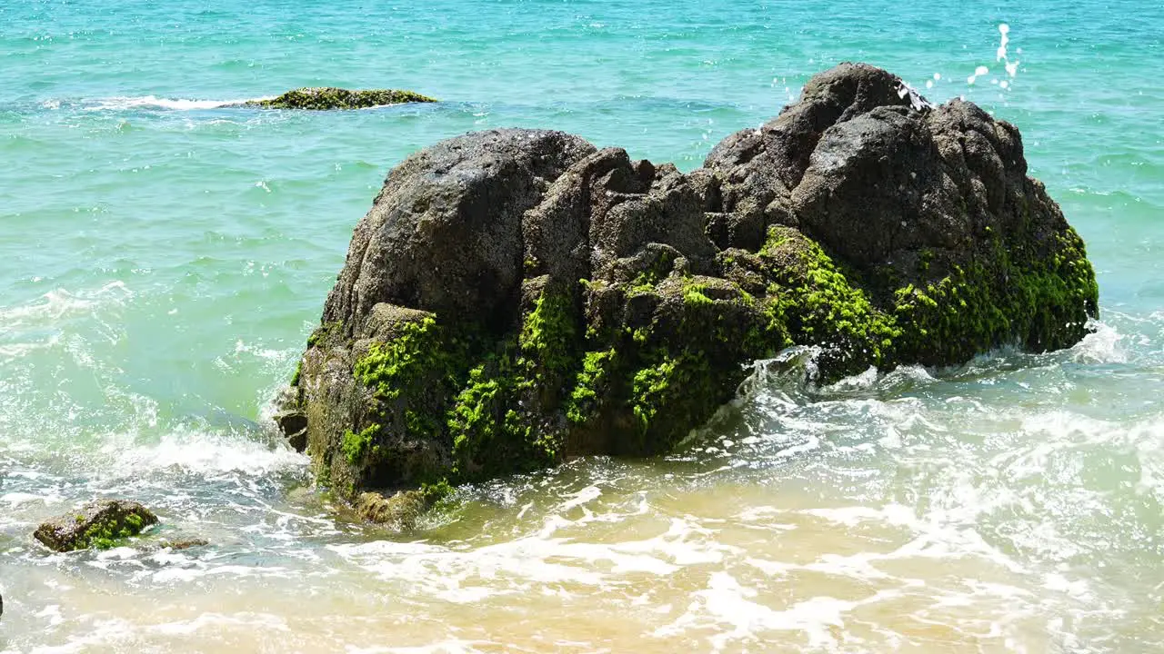 Ocean waves crashing on the rock in the middle of the beach