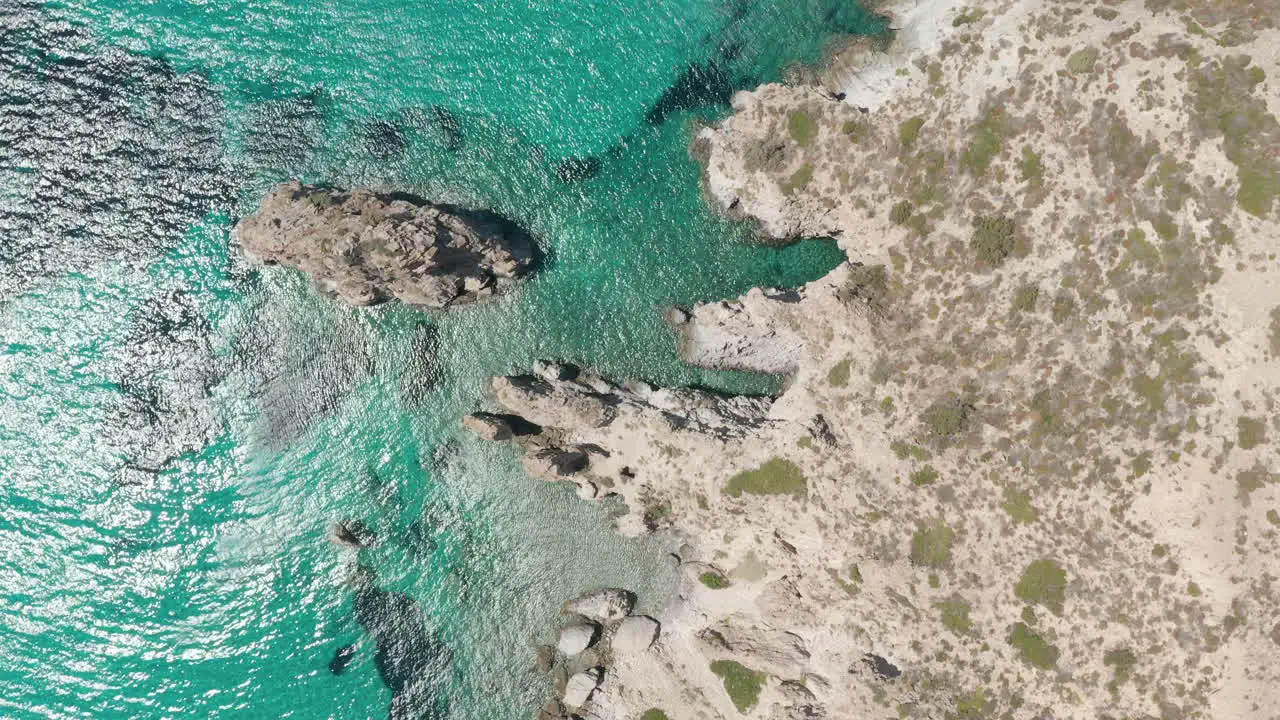 Overhead Top Down Aerial Flight over Greek Island Milos Turquoise Blue Ocean with Rocky Cliff Coast