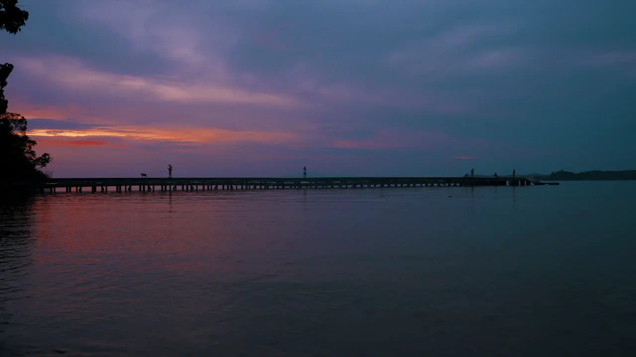 Gentle ocean waves caress the lonely beach in Koh Chang Thailand while the sky is ablaze with the warm hues of a breathtaking sunset – a vivid canvas of orange purple and red