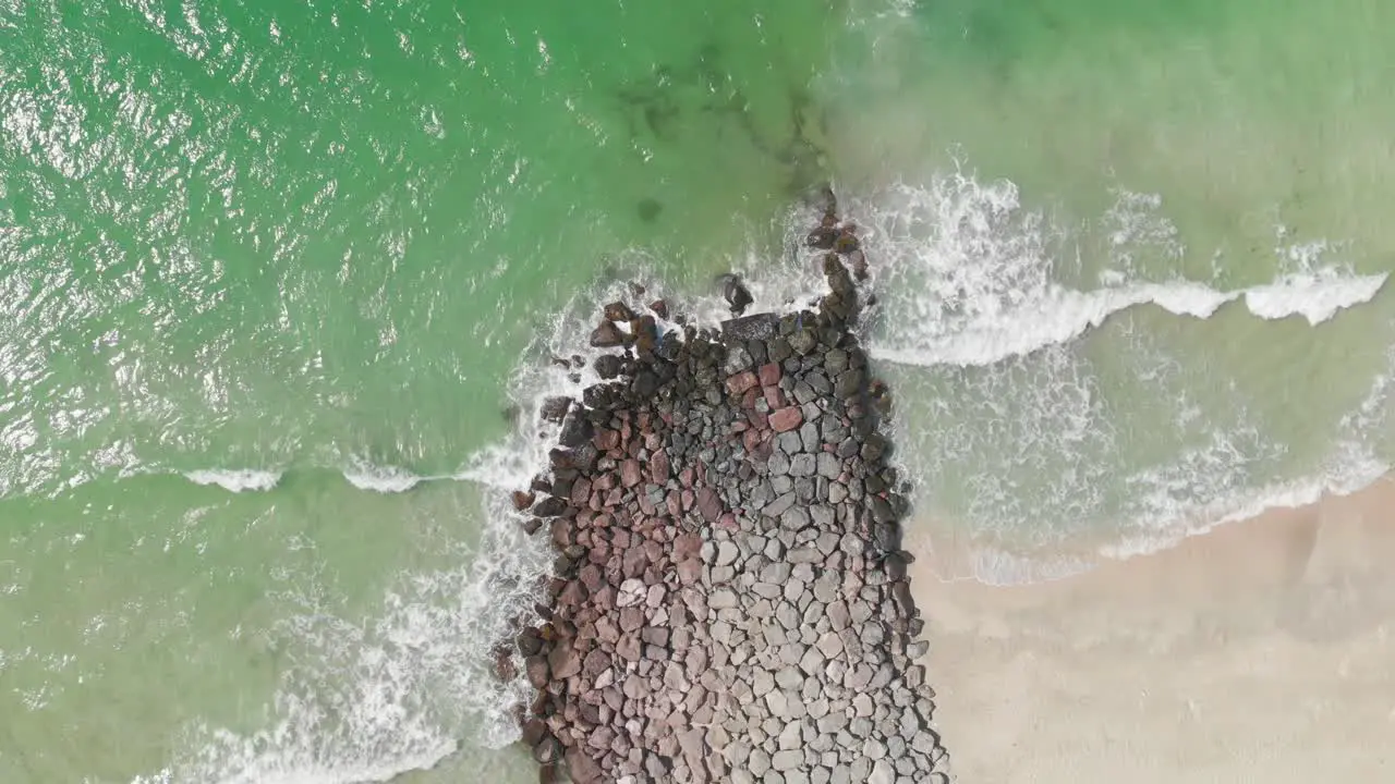 Aerial view of waves breaks on rocks Bird's eye view of ocean waves crashing against the bare stones Deep blue sea with crashing waves and foam on rocks