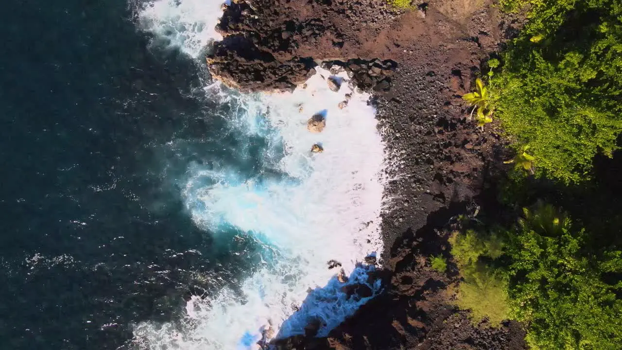 Expansive top-down drone shot highlights the serene blue ocean reaching the subtle cliff edges on Big Island Hawaii