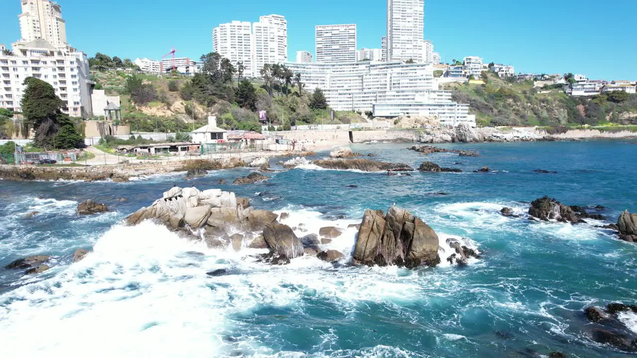 Ocean Waves Hitting the Coastal Rocks in Viña del Mar with Buildings in the Background Chile