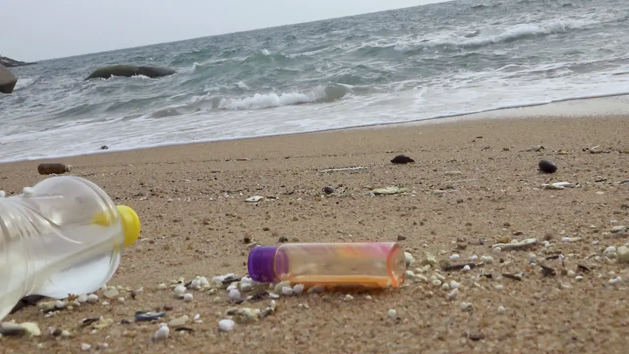 Various of littered bottle trash dumped on beachfront horizontal zoom out shot