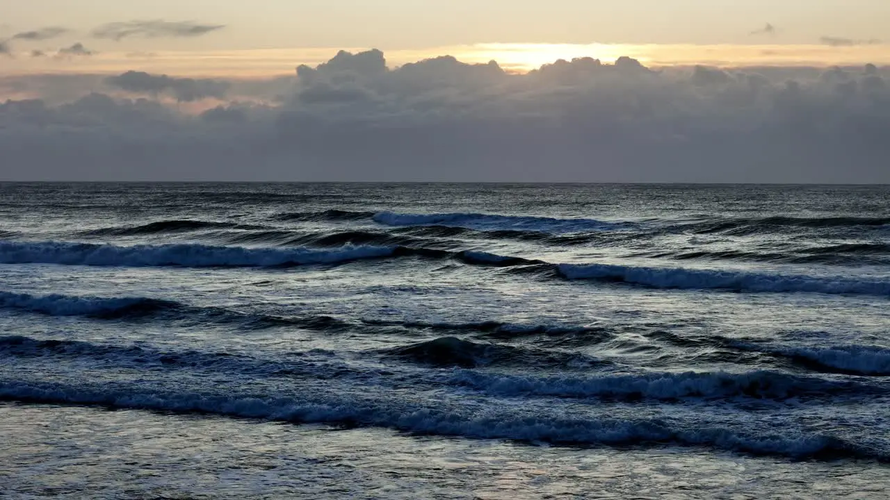 Dusk settles over tumultuous ocean waves Cloud-lined skies above the twilight sea