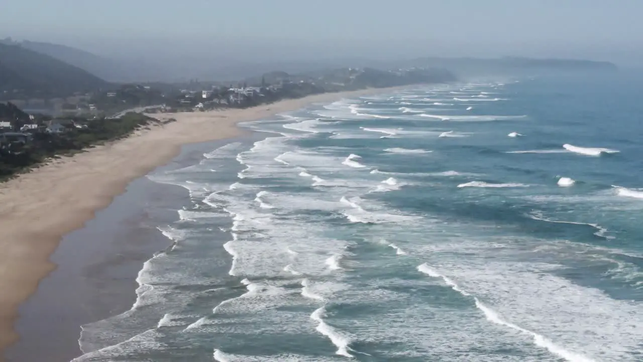 South Africa Wilderness Coast long Sandy Beach with many Ocean Waves crashing ashore and Beach Houses in the background