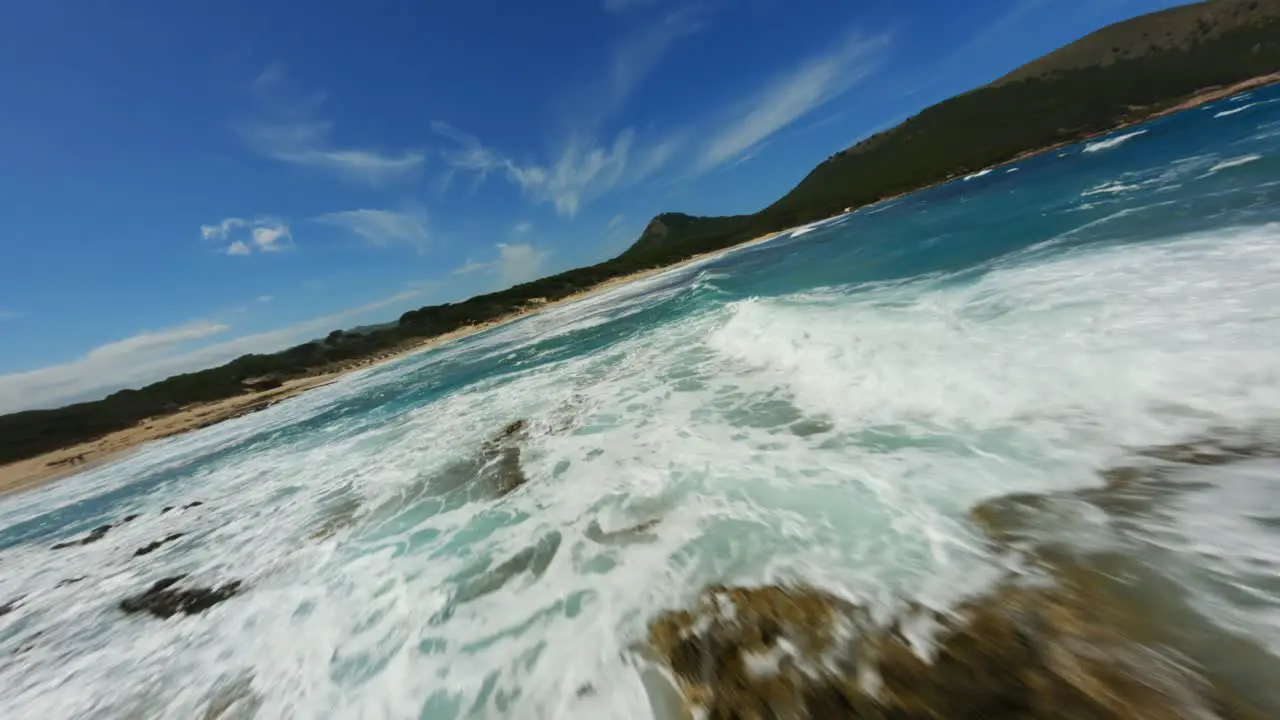 FPV Drone surfing over amazing surf water waves with clear blue water on a beautiful day