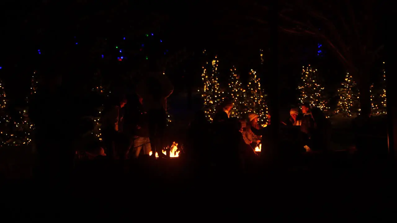 Families gather around a firepit at a park at Christmas season at night