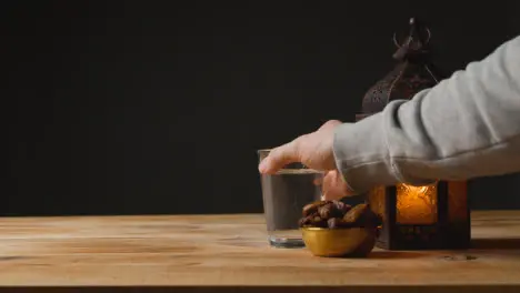 Stationary Shot of Hand Taking a Drink of Water On a Table for Ramadan