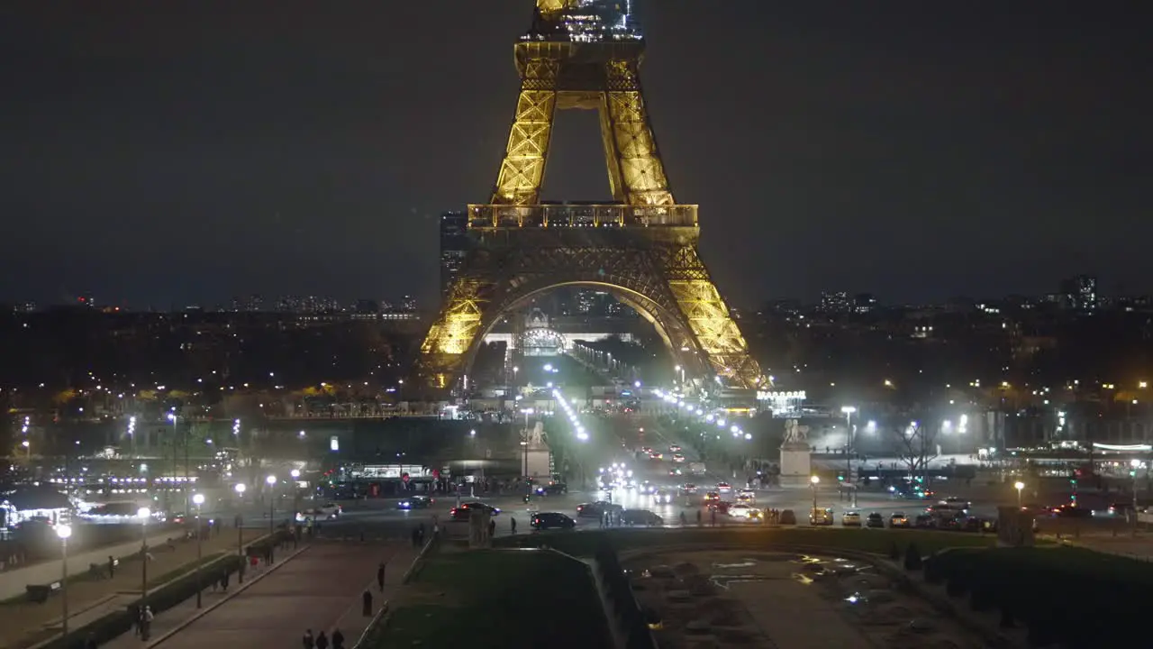 Eiffel Tower illuminated in the middle of the night and the lights of the cars driving by