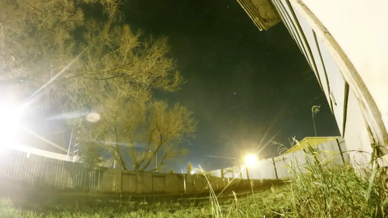 NIGHT LAPSE Moon going down and stars flying by over a tree in a yard next to a home