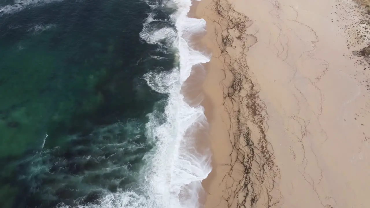 Arial shot flying along a beach and ocean waves