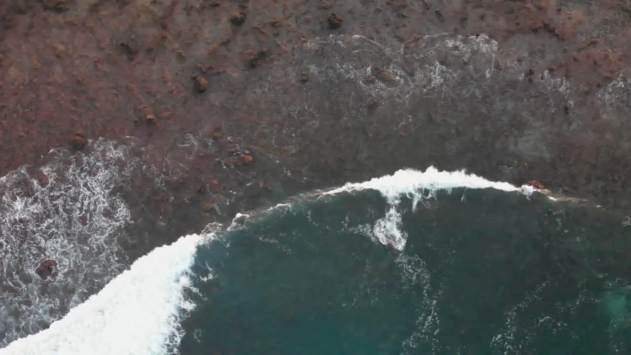 Aerial drone footage of ocean waves washing the volcanic shore