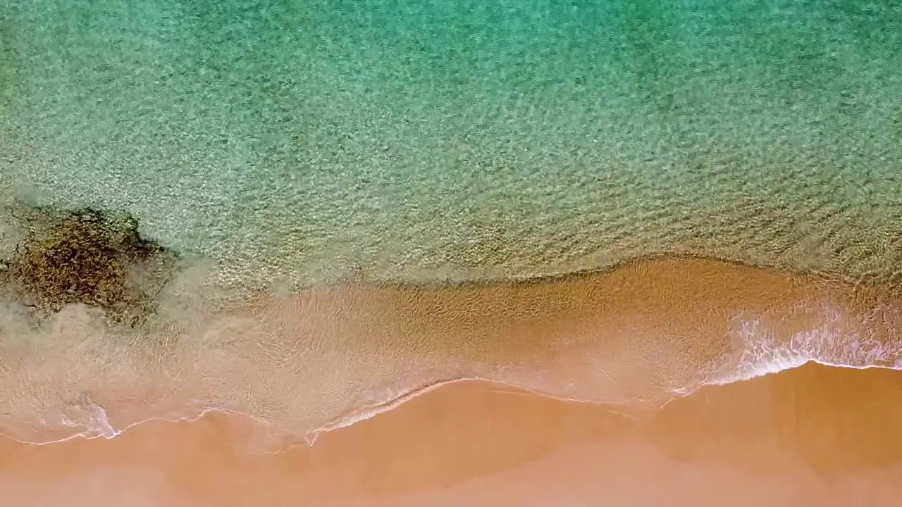 Aerial birds-eye view of crystal blue water waves on shore