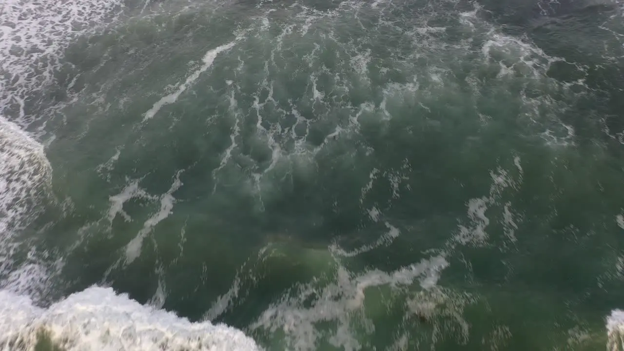 Discover the beauty of the rugged cliffs in the background as the drone shot slowly pans down to reveal the mesmerizing crashing waves below