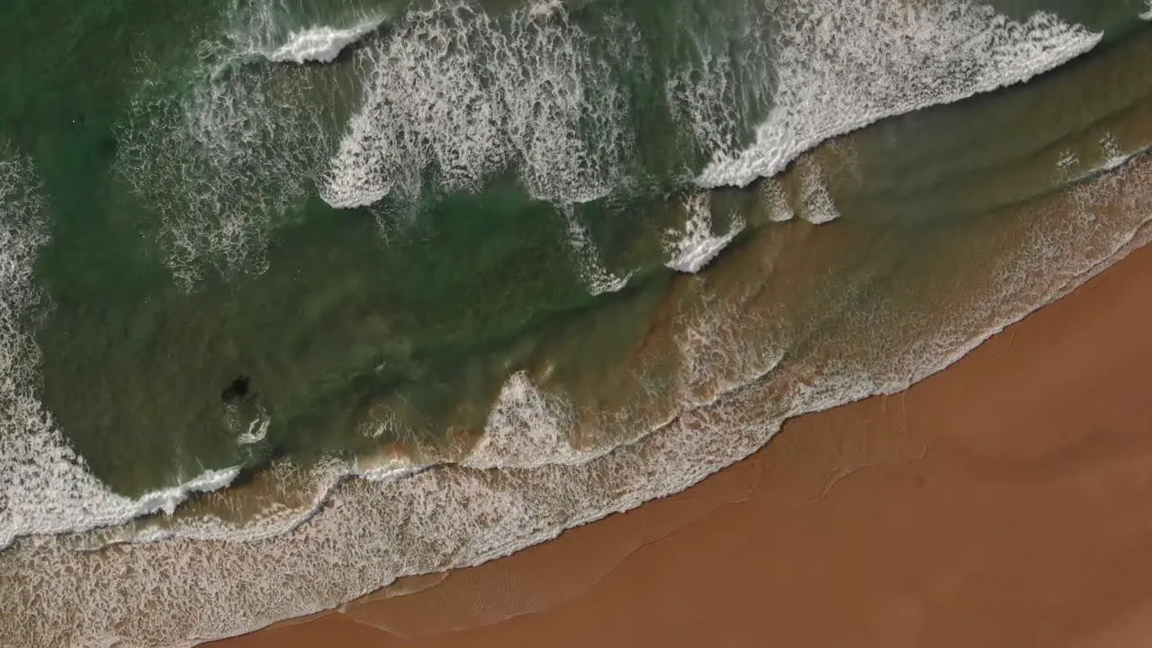 Gentle waves run out onto pristine Malhão beach Portugal