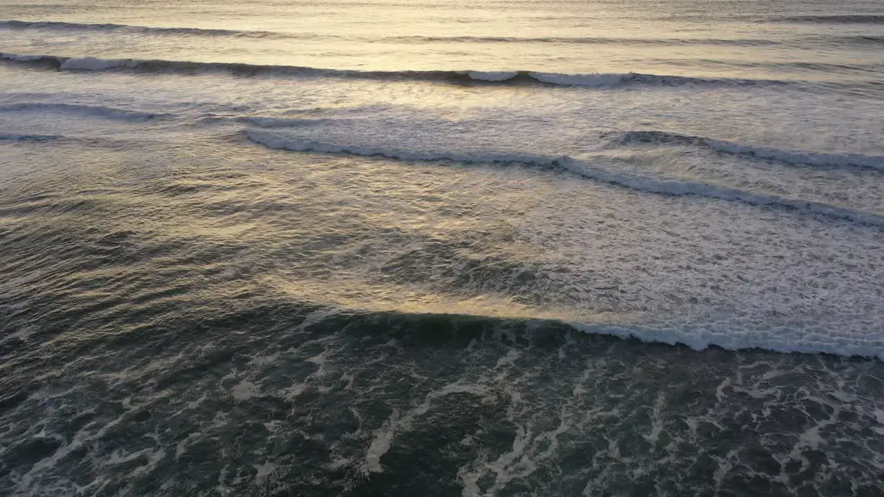 Experience the raw power of the ocean as our drone captures the crashing waves below and pans up to reveal a breathtaking sunset on the horizon