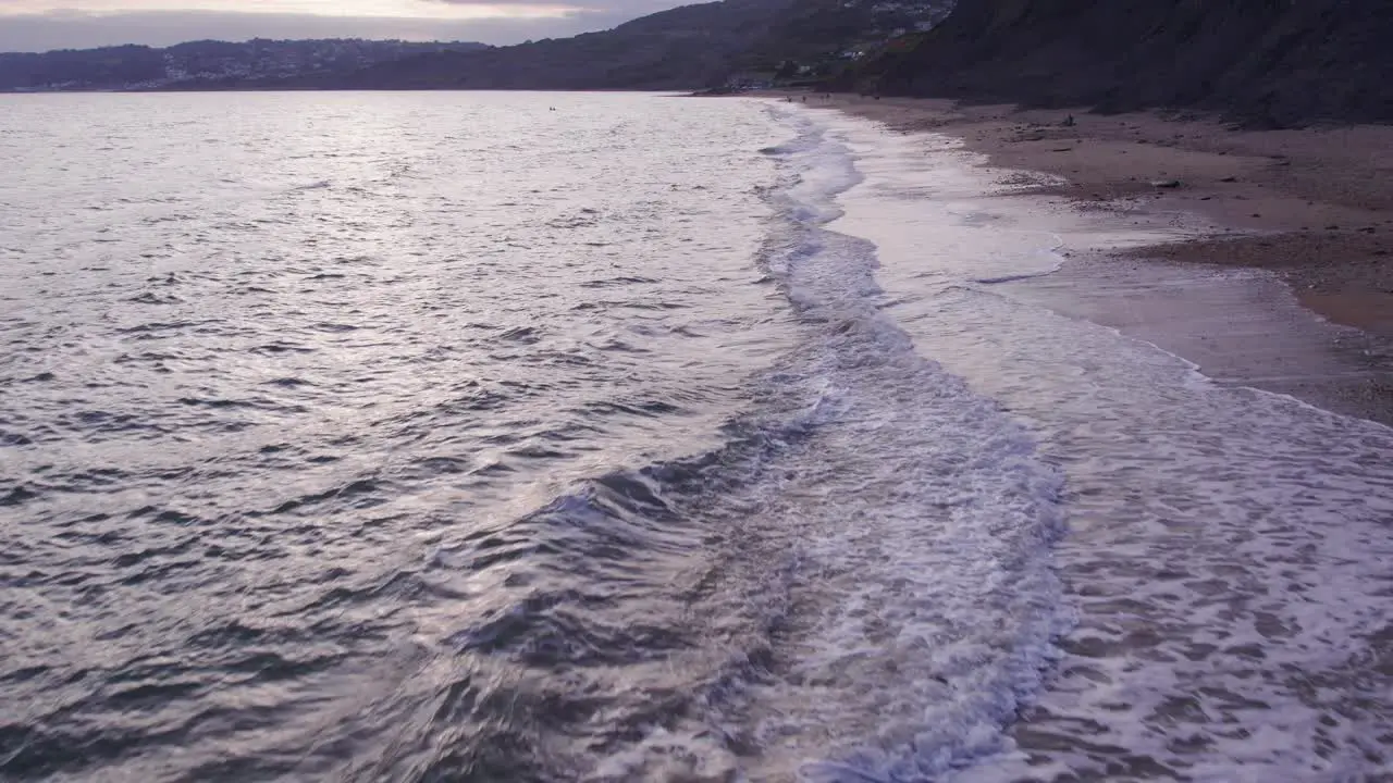 Slow motion drone shot moving backwards of waves crashing on the beach Jurassic Coast Dorset UK