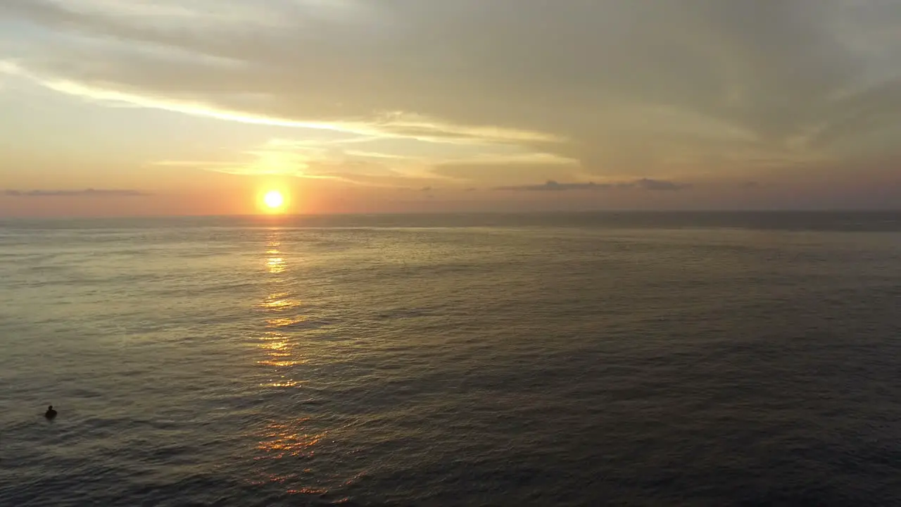 Aerial View Of Surfers On Surfboards In Rough Sea At Sunset