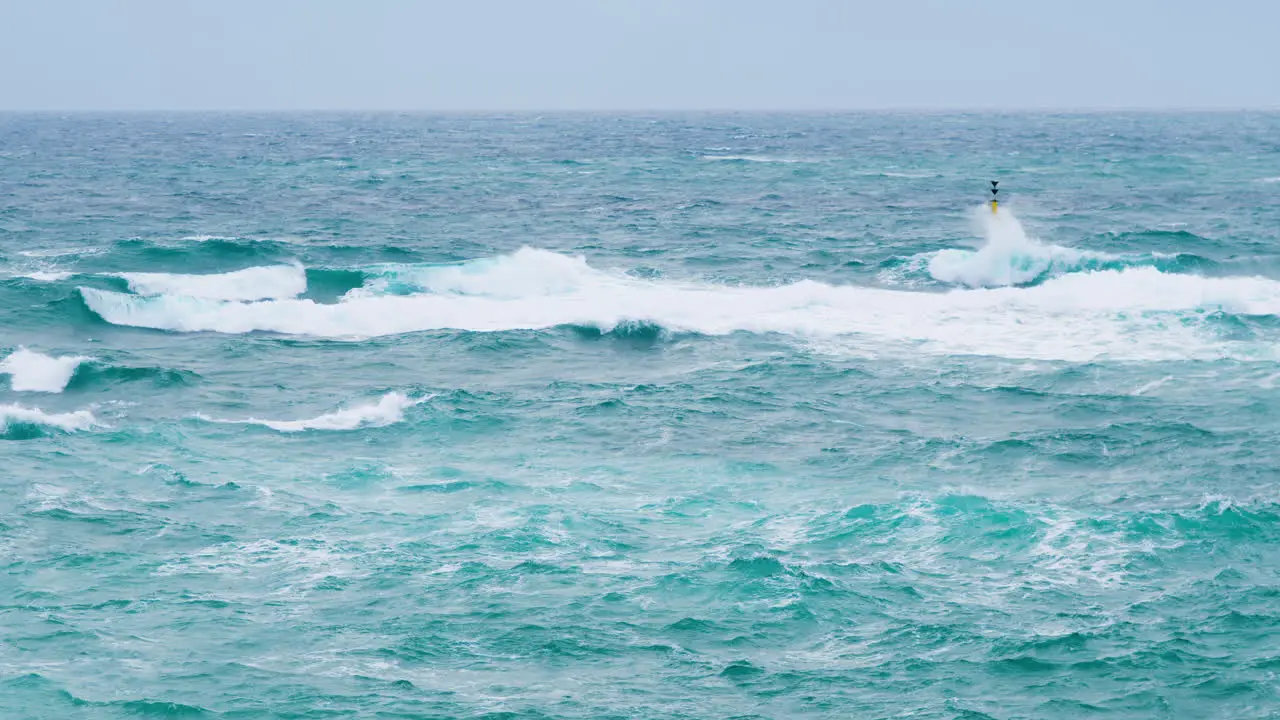 Waves breaking on yellow cardinal mark stormy weather and restless sea